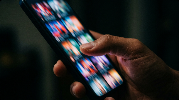 Close-up of a thumb swiping on a smartphone screen with motion blur showing fast scrolling through colorful video thumbnails