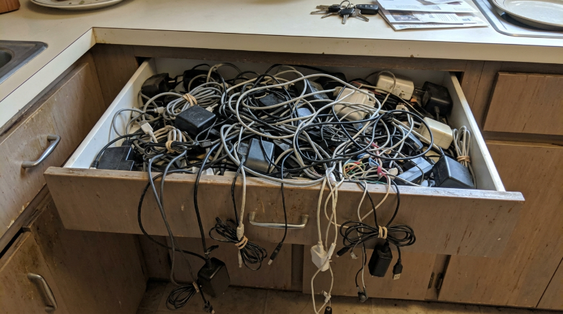Kitchen drawer overflowing with old tangled chargers and cables